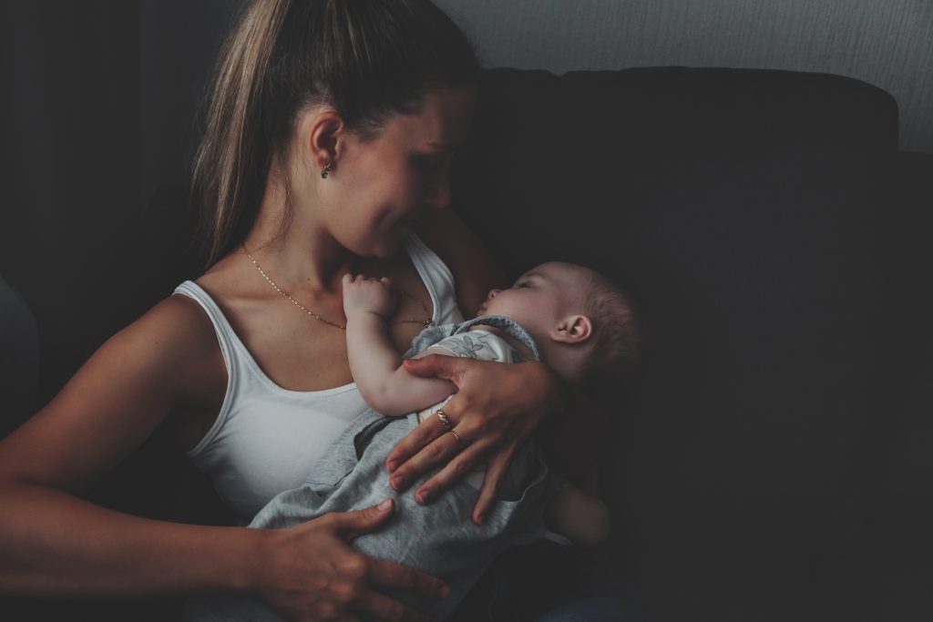 Young mother tenderly holding newborn baby in peaceful home setting at Imago Dei Ministry Homes maternity program in Longview WA
