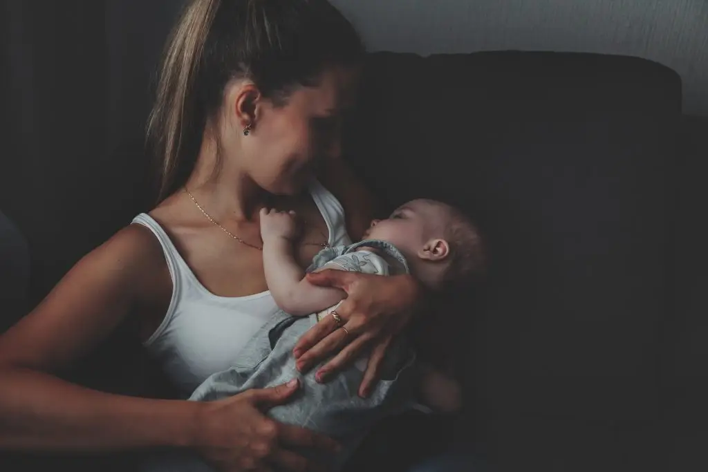 Young mother tenderly holding newborn baby in peaceful home setting at Imago Dei Ministry Homes maternity program in Longview WA